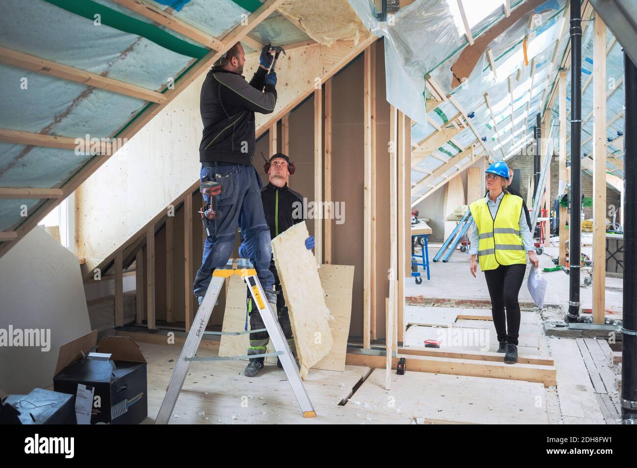 Responsabile femminile che guarda i lavoratori manuali che lavorano nel cantiere Foto Stock