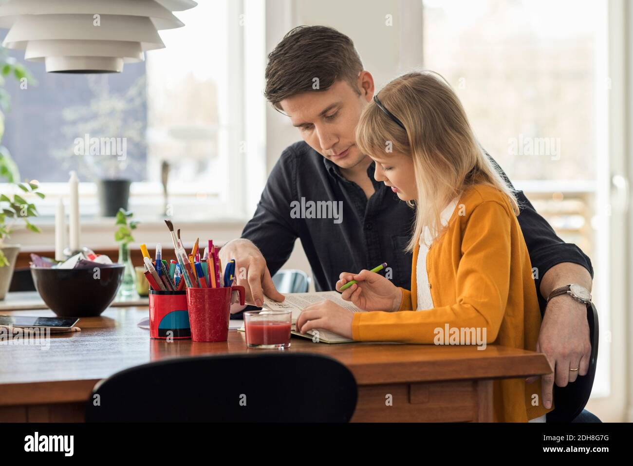 Padre che assiste la figlia nei compiti a casa Foto Stock