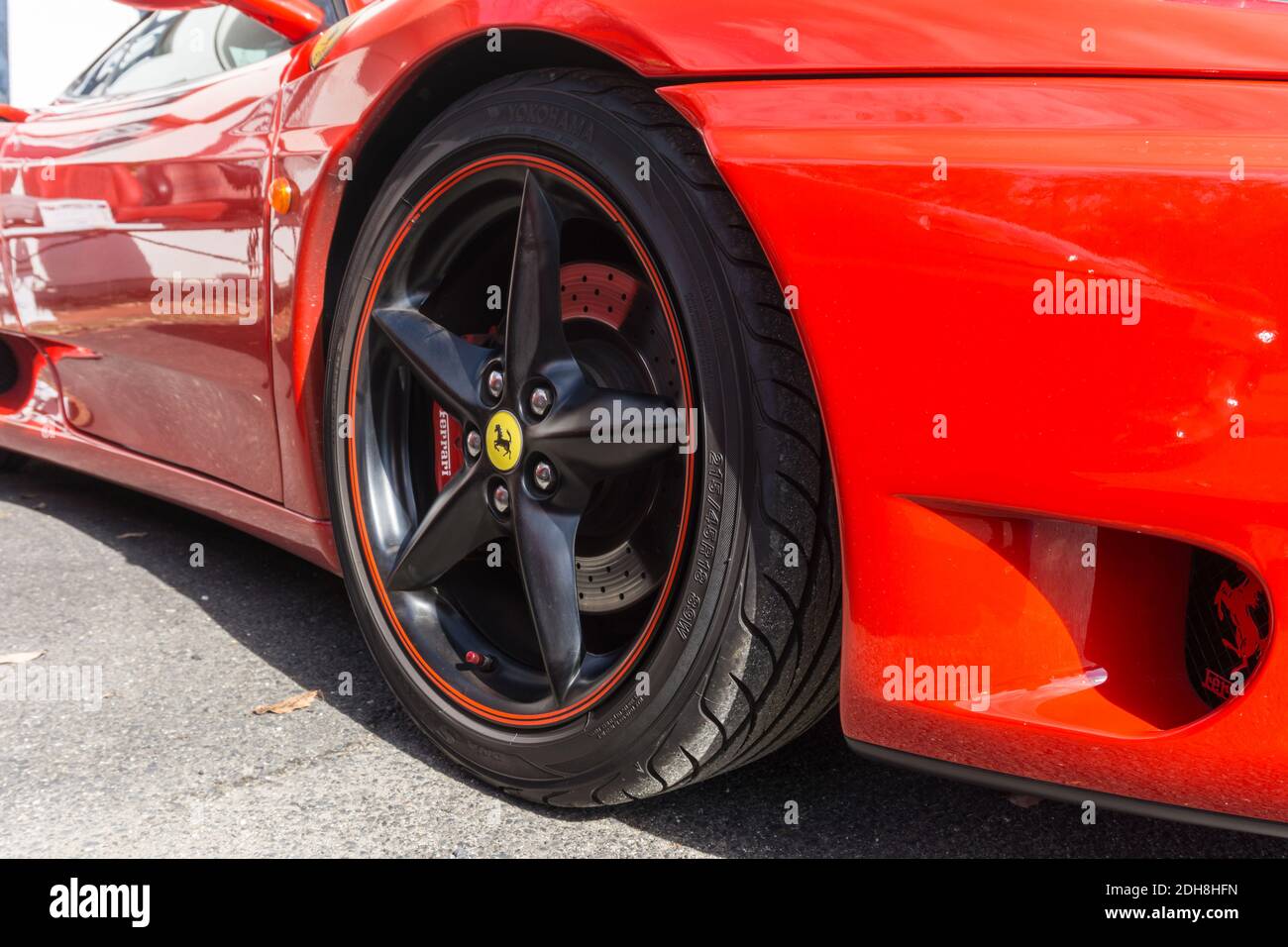 Primo piano del cerchio in lega nera su Una Ferrari rossa rosso corsa 360 Modena sport coupé Foto Stock