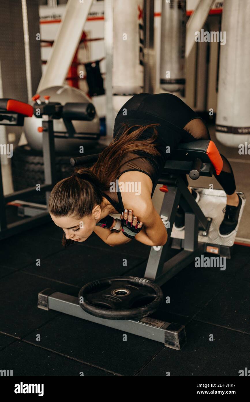 Donna in forma che fa iperestensione durante l'allenamento in palestra presso il centro fitness. Foto Stock