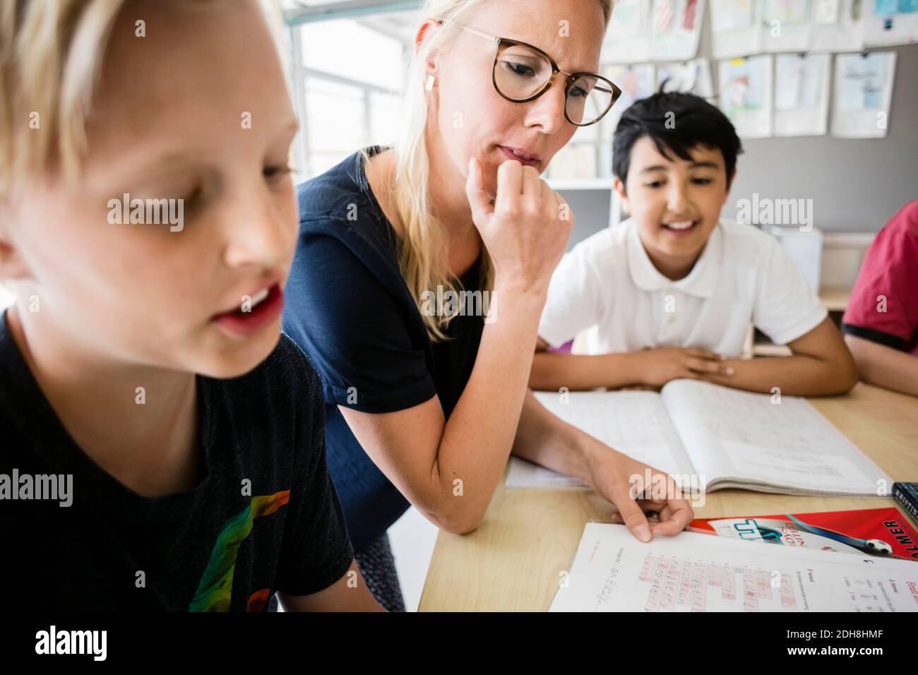 Insegnante e studenti che leggono dal libro in classe Foto Stock