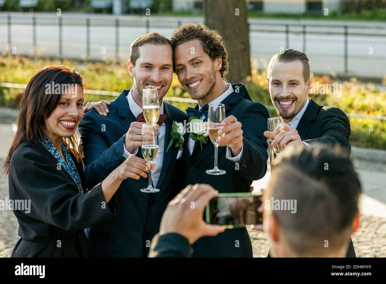 Amici felici con flauti champagne in posa per la fotografia durante il matrimonio cerimonia Foto Stock