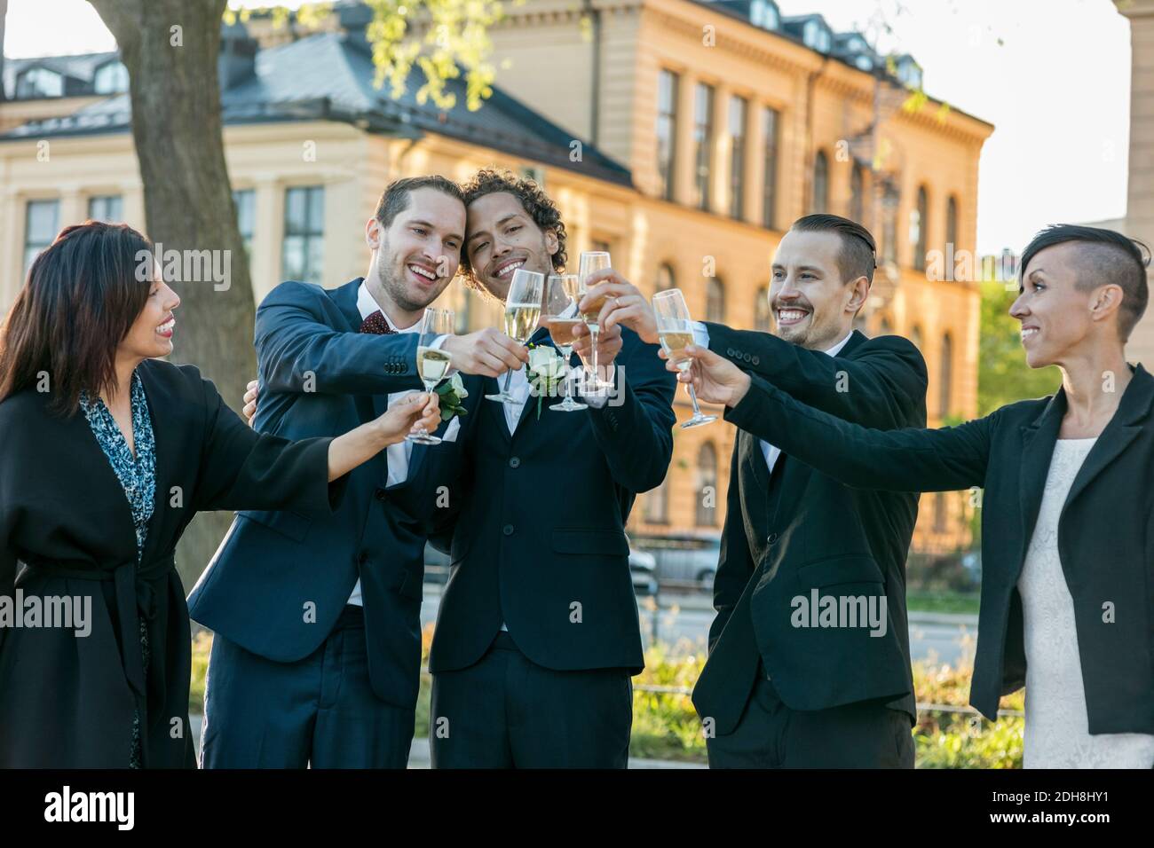 Amici felici che alzano flauti di champagne per il brindisi durante la cerimonia nuziale Foto Stock