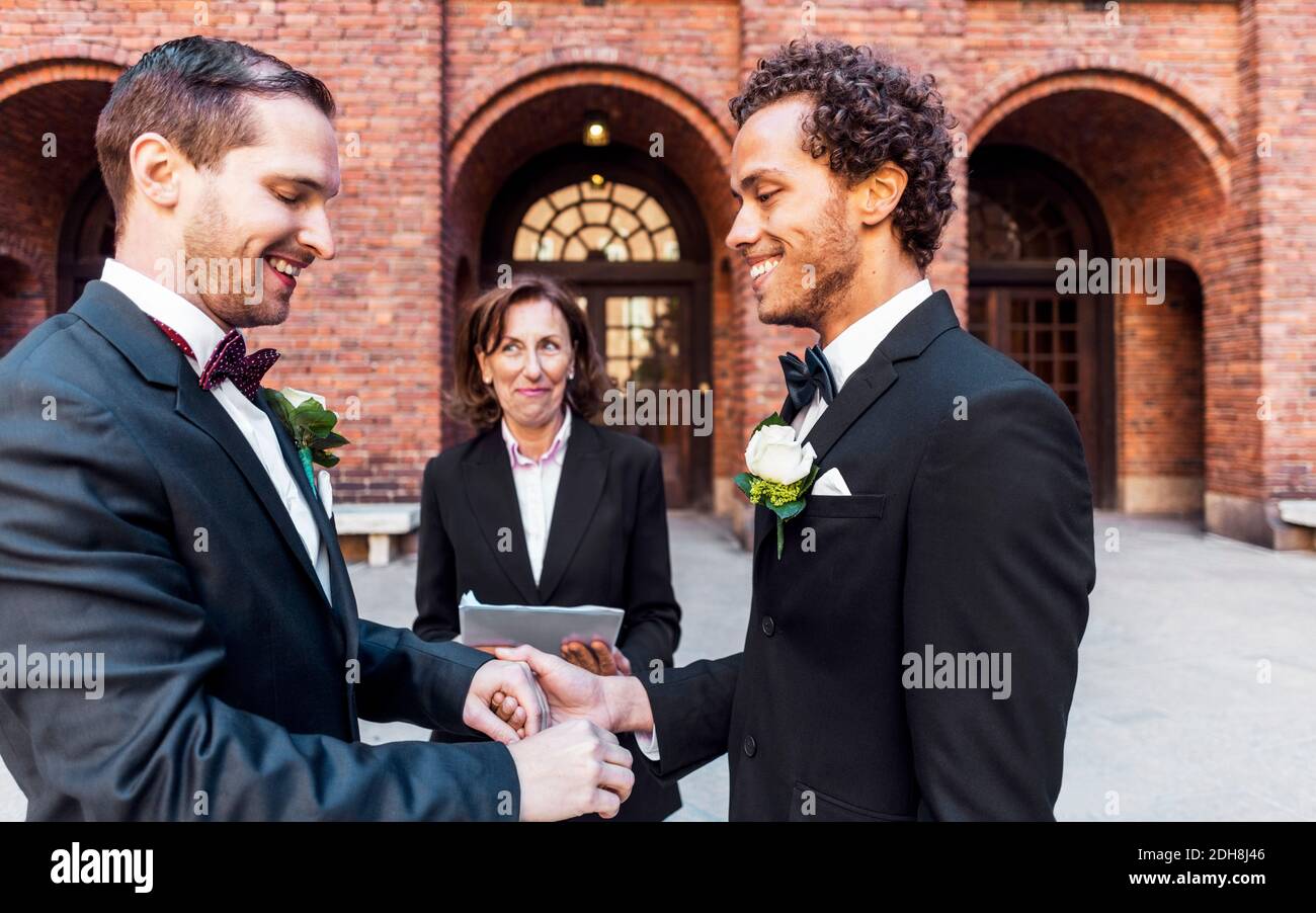 Sacerdote che guarda l'uomo che tiene la mano del compagno gay durante il matrimonio cerimonia Foto Stock