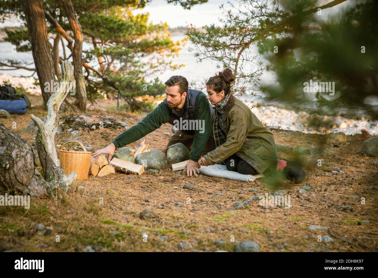 Coppia seduta dal fuoco pit al campeggio in foresta Foto Stock