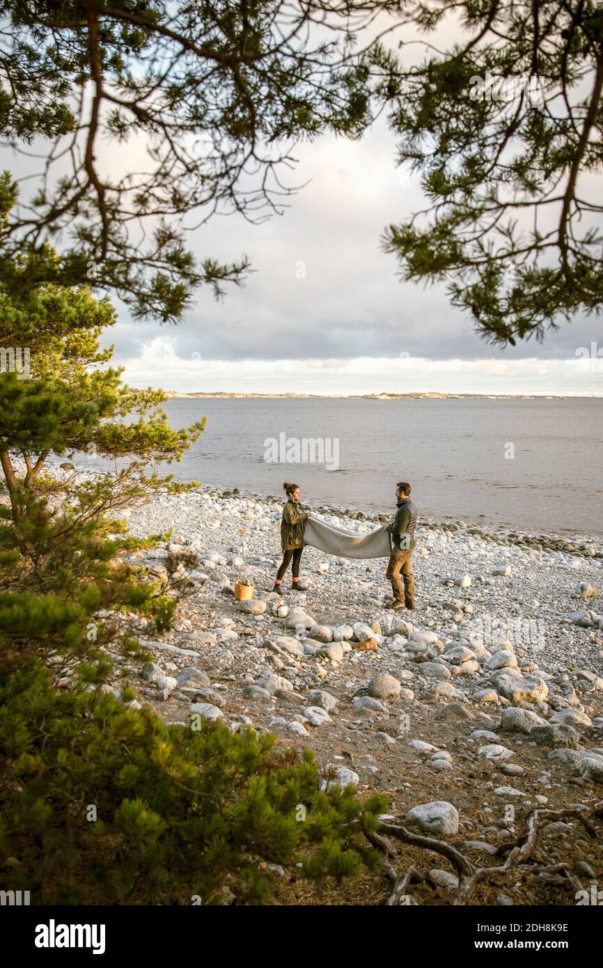 Coperta di posizionamento coppia sulla costa rocciosa della spiaggia durante il tramonto Foto Stock
