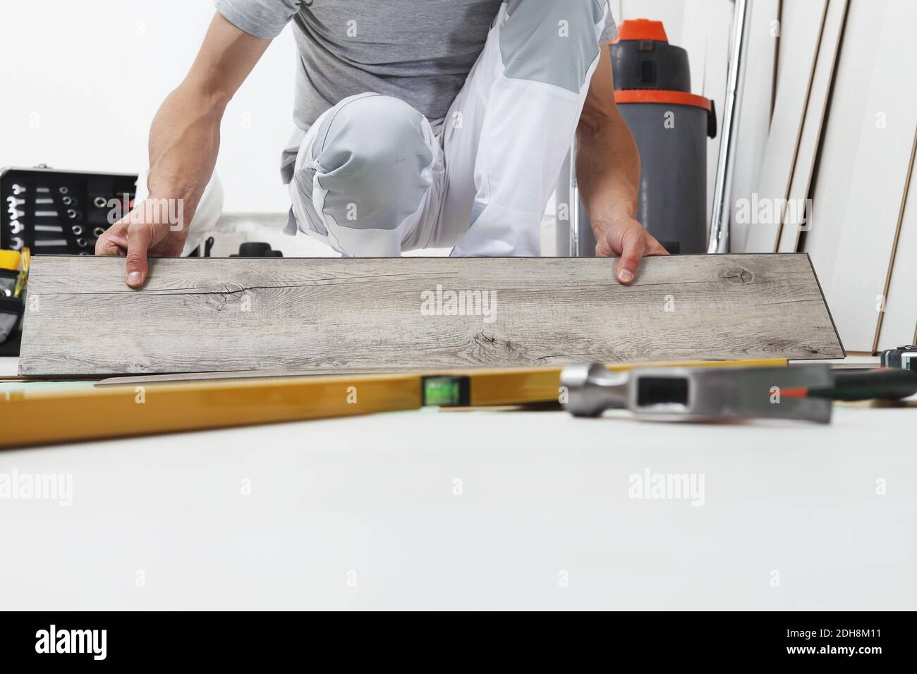 Mani di lavoro che installano pavimento in vinile laminato di legno. Ristrutturazione di case con pavimenti in legno. Foto Stock