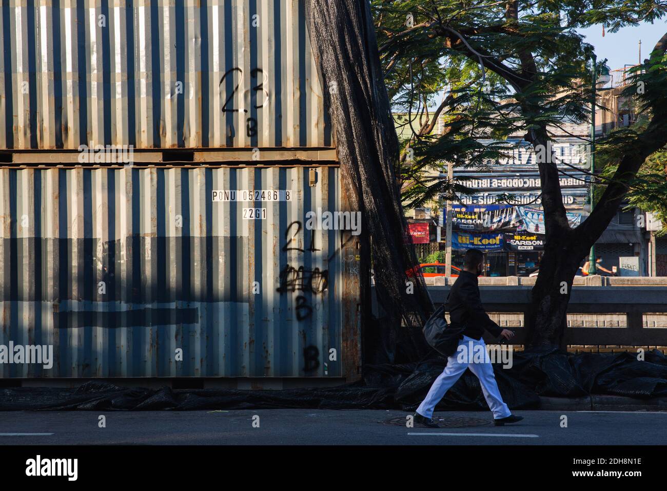 Un uomo cammina oltre il container intermodale che è stato istituito dalla polizia come un blocco stradale durante il rally.Thai polizia ufficiali bloccati diverse strade a Bangkok con container intermodali e filo spinato per fermare i dimostranti. Per celebrare la Giornata della Costituzione e la Giornata internazionale dei diritti umani, i manifestanti thailandesi hanno chiesto la riforma della monarchia e hanno abrogato la Legge maggiore lese prima di inviare la loro lettera di richiesta di aiuto all'ufficio delle Nazioni Unite a Bangkok. Foto Stock