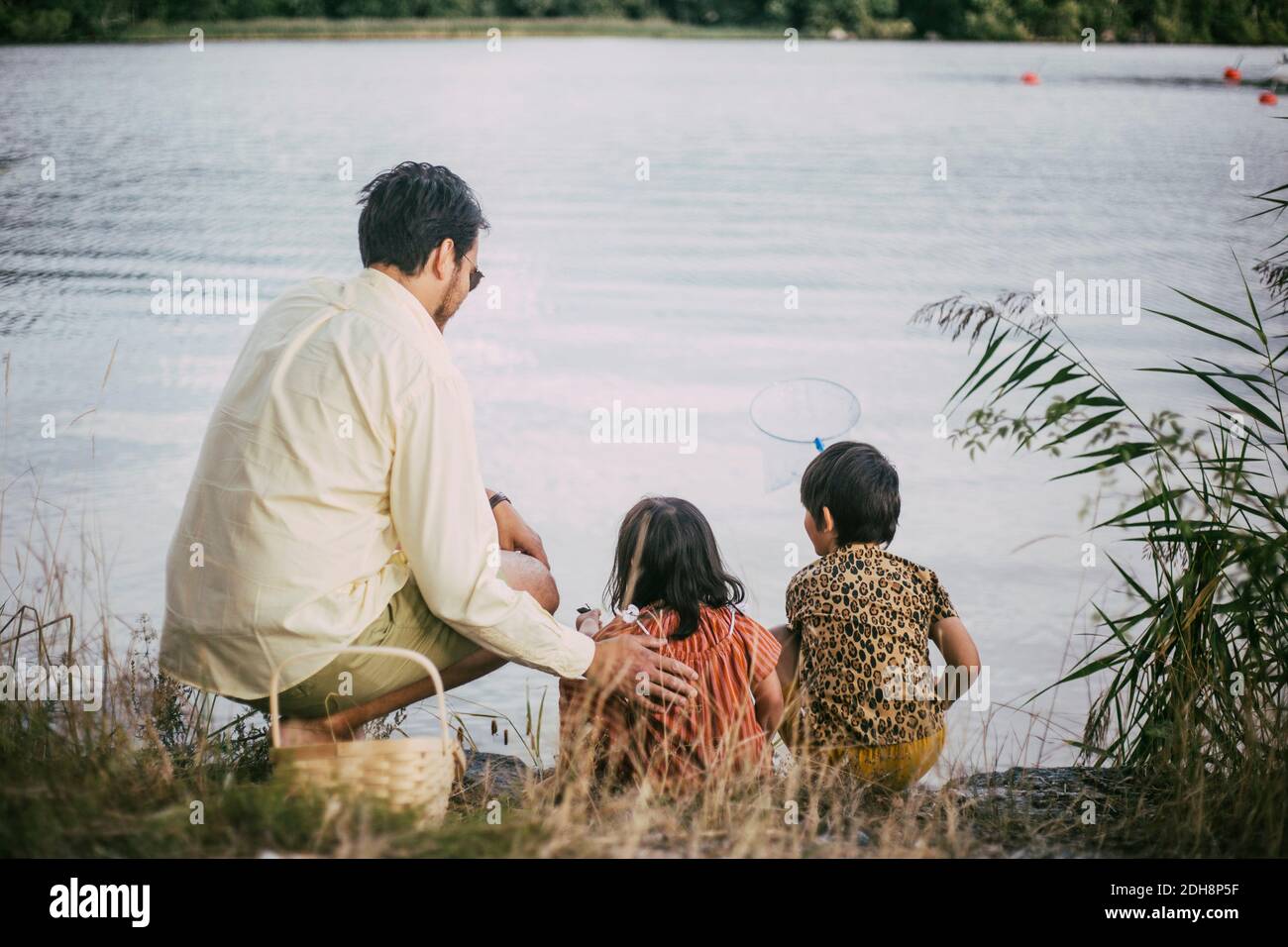 Vista posteriore del padre con la sindrome di Down figlia pesca vicino lago Foto Stock