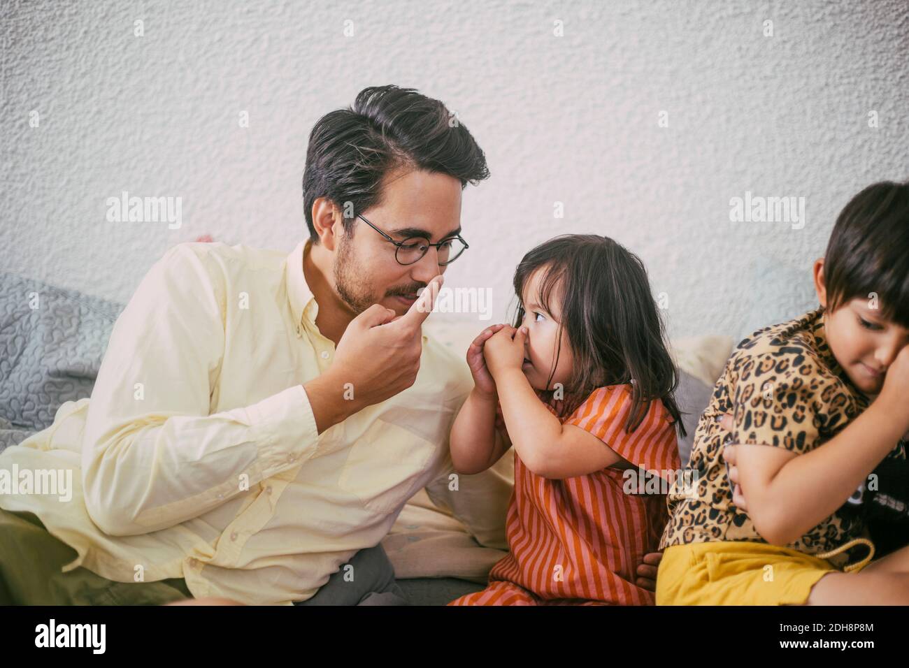 Sorridente padre che insegna la figlia mentre punta al naso contro il muro Foto Stock