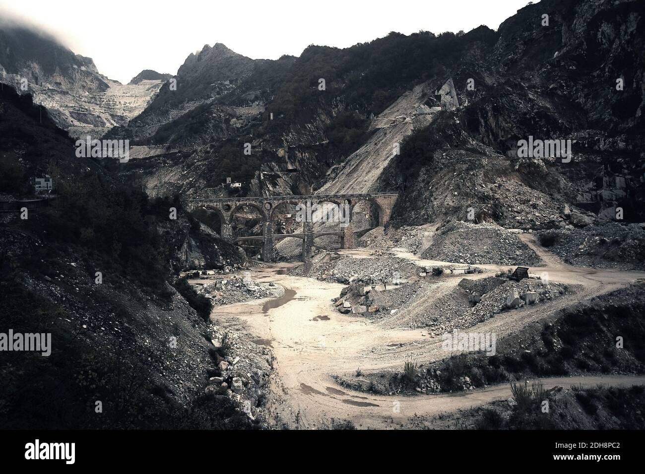 Un vecchio ponte si estende su una cava di marmo bianco nelle Alpi Apuane vicino a Carrara, Toscana, Italia, che mostra la ricca storia della regione nell'estrazione del marmo . Foto Stock