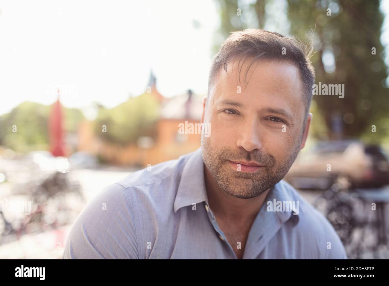 Ritratto di un uomo d'affari sicuro che ascolta la musica con le cuffie intrauricolari giorno di sole Foto Stock