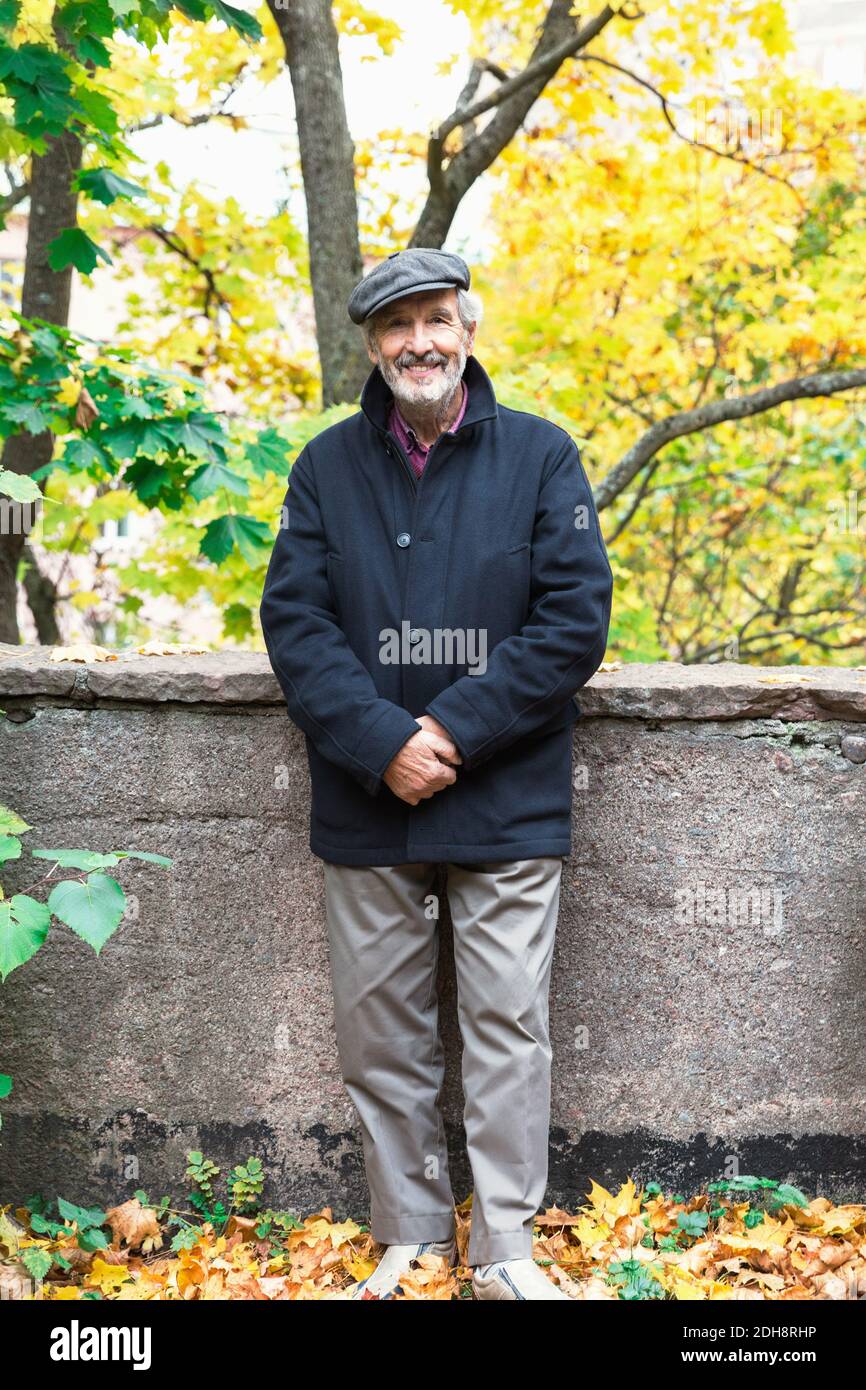 Ritratto di felice anziano in piedi con le mani aggrappate parco durante l'autunno Foto Stock