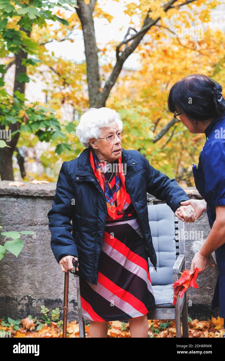 Custode che assiste donna anziana nel parco Foto Stock