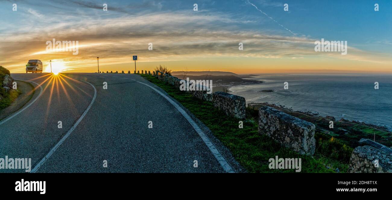 Un camper parcheggiato in cima a una montagna sul mare all'alba con una vista grande della riva e. oceano Foto Stock