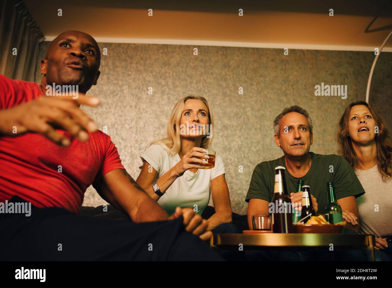 Vista ad angolo basso delle coppie che guardano gli sport insieme di notte Foto Stock