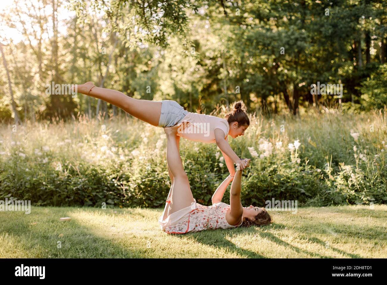 Sorridente sorella equilibrante ragazza sulla gamba in cortile Foto Stock