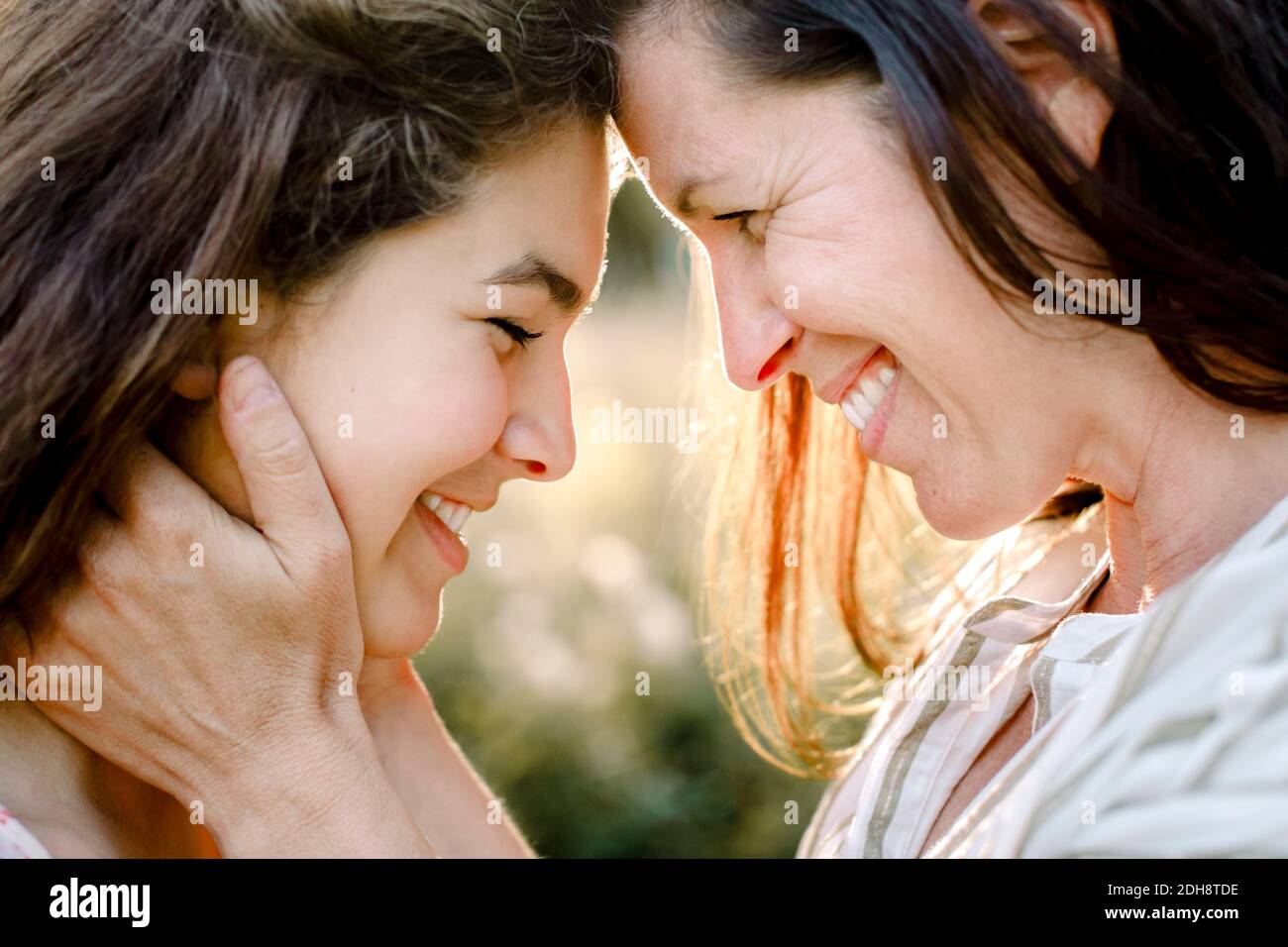 Madre sorridente che abbraccia la figlia in cortile Foto Stock
