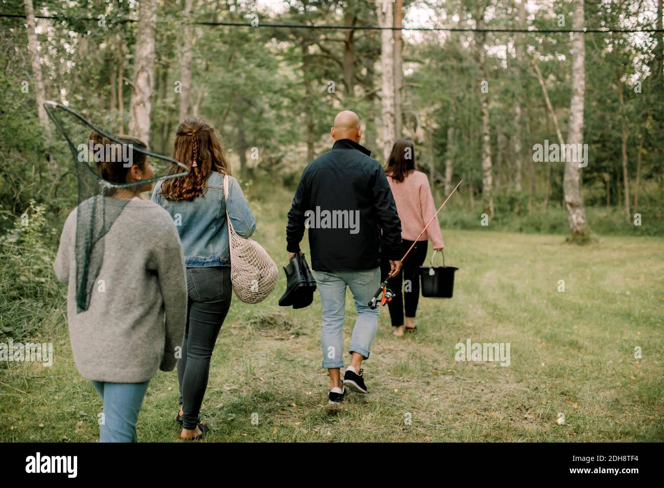 Vista posteriore delle figlie con la famiglia che cammina nella foresta durante vacanze Foto Stock
