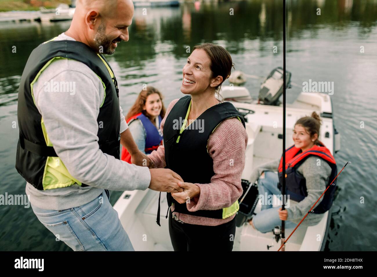 Figlie che guardano i genitori che tengono le mani mentre si siedono in barca Foto Stock