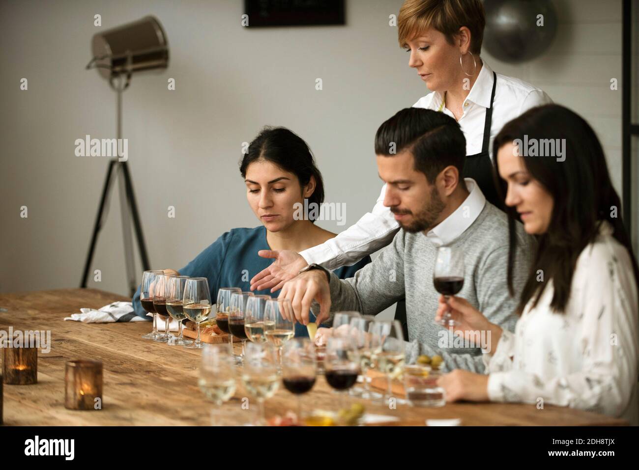 Gli uomini d'affari gustano vari vini mentre si siedono a tavola Foto Stock