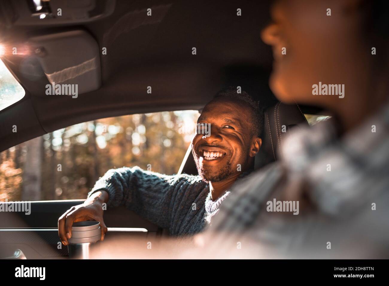 Uomo sorridente che guarda l'amico femmina in auto durante la strada viaggio Foto Stock