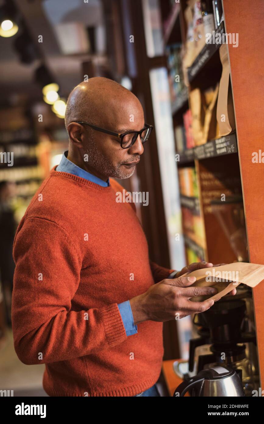 L'uomo anziano legge etichetta sul pacchetto di cibo mentre lo shopping a. negozio Foto Stock