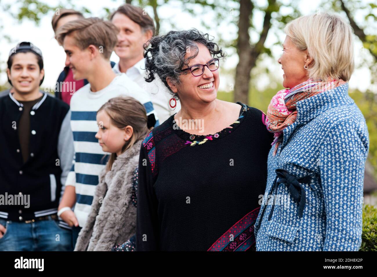 Felici donne multietniche che parlano in piedi con amici e familiari in cortile Foto Stock