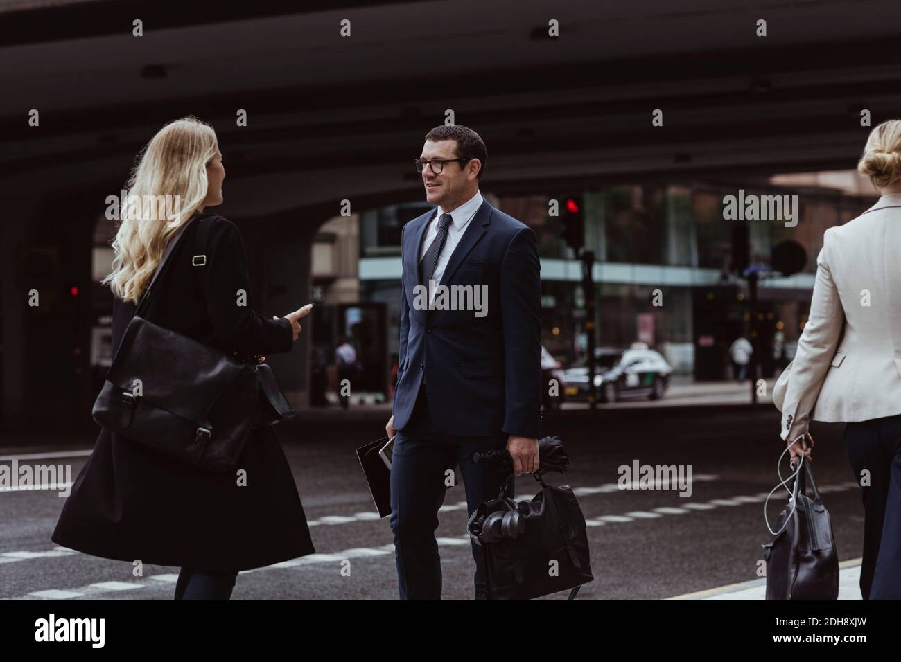 Uomo d'affari con borsa che parla con il collaboratore mentre si cammina in città Foto Stock
