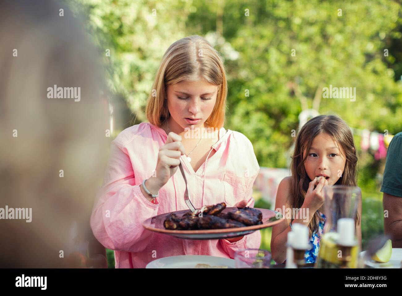 Le ragazze mangiano il pranzo nel cortile posteriore durante la festa in giardino Foto Stock