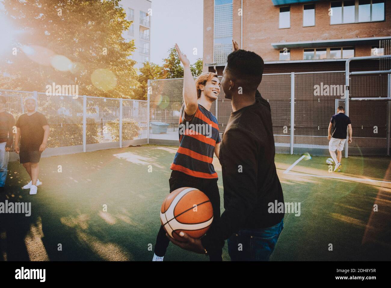 Sorridendo amici che danno high-five mentre giocano gli sport nel campo Foto Stock