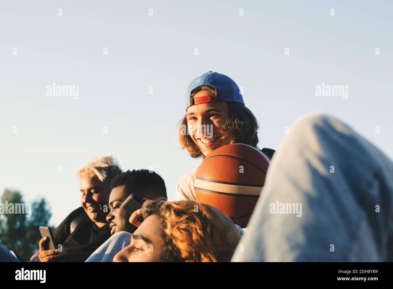Sorridente adolescente maschile con gli amici che si divertono contro il cielo limpido Foto Stock