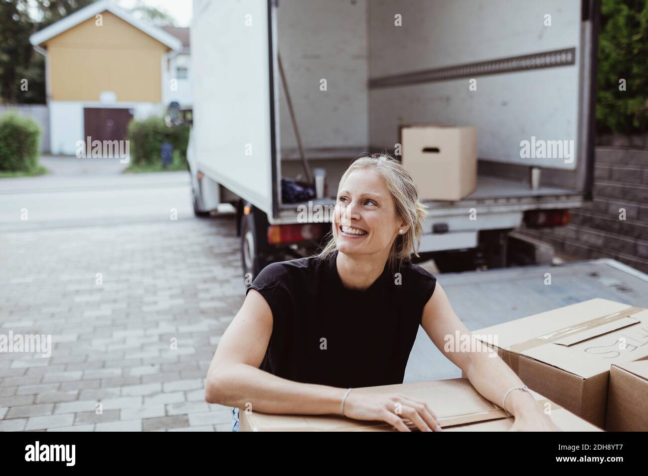 Sorridente femmina da scatola di cartone guardando via fuori furgone Foto Stock