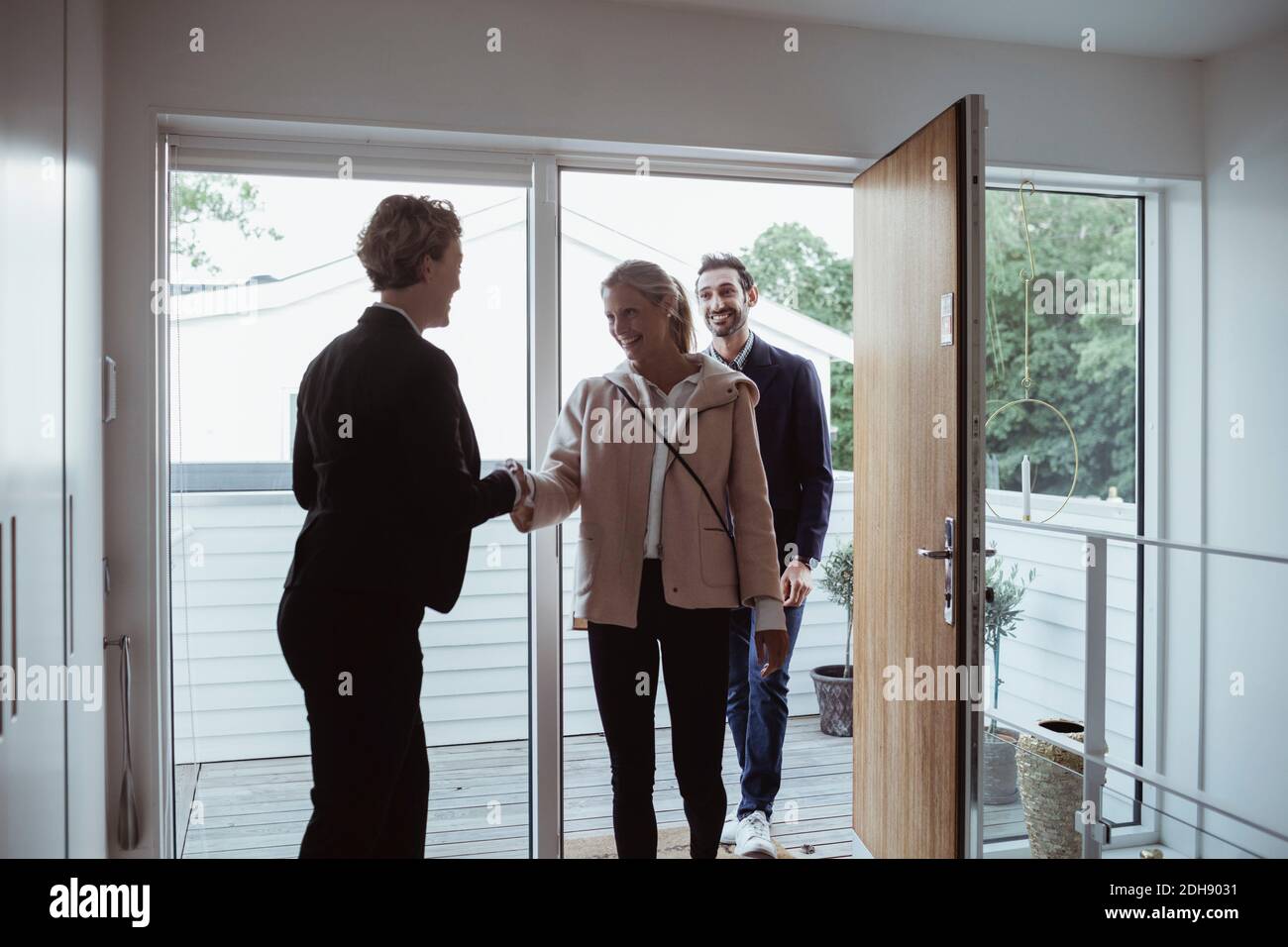 Sorridente agente immobiliare saluto coppia in nuova casa Foto Stock