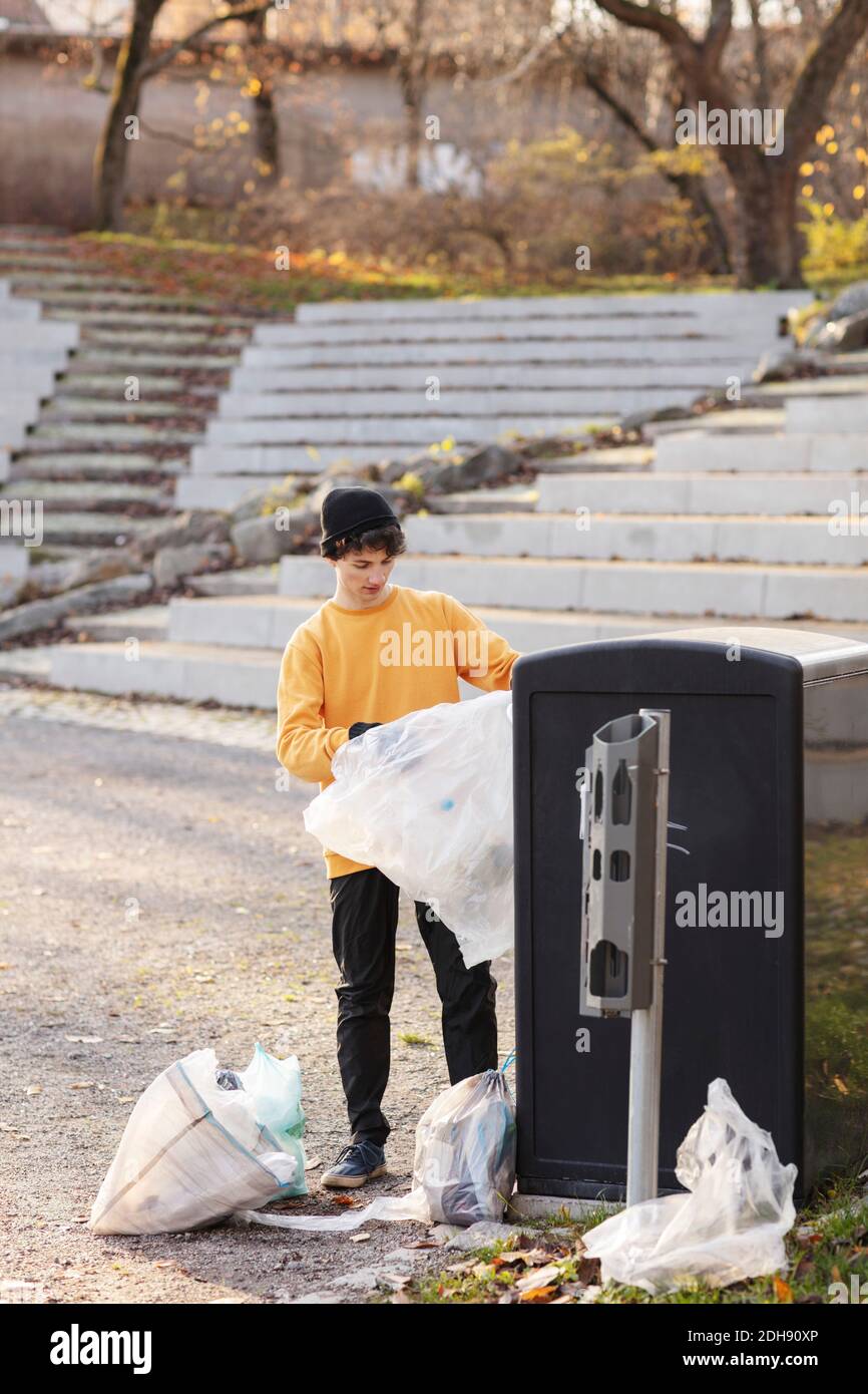 Volontario maschile con rifiuti di plastica in piedi da rifiuti può Foto Stock