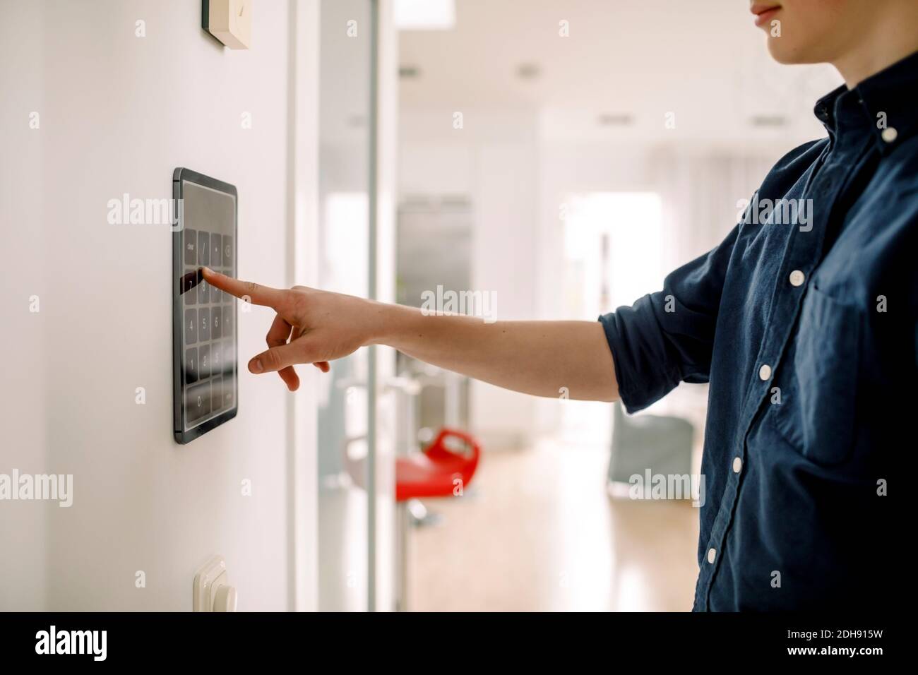 Sezione centrale del ragazzo adolescente che immette il codice di autorizzazione sulla tecnologia wireless a parete a casa Foto Stock