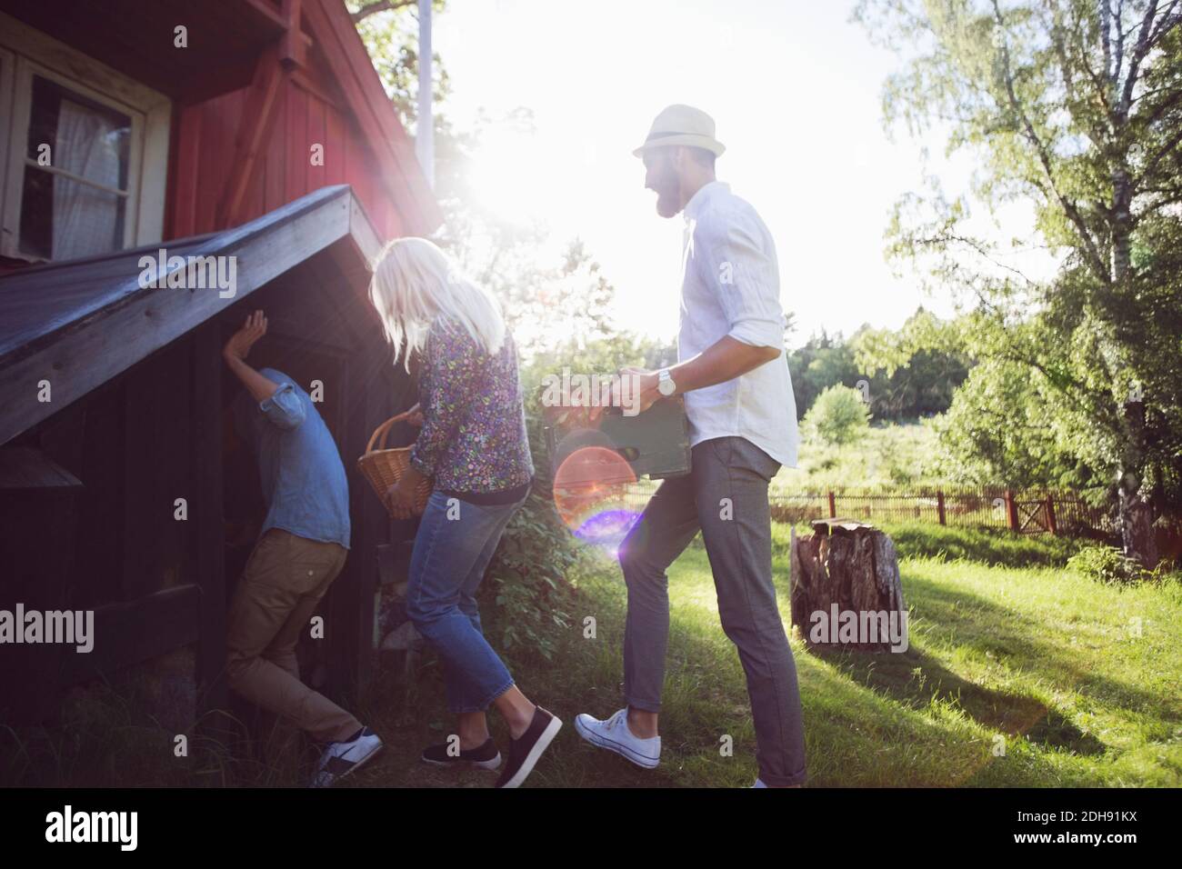 Amici che tengono cassa e contenitori mentre entrano cottage Foto Stock