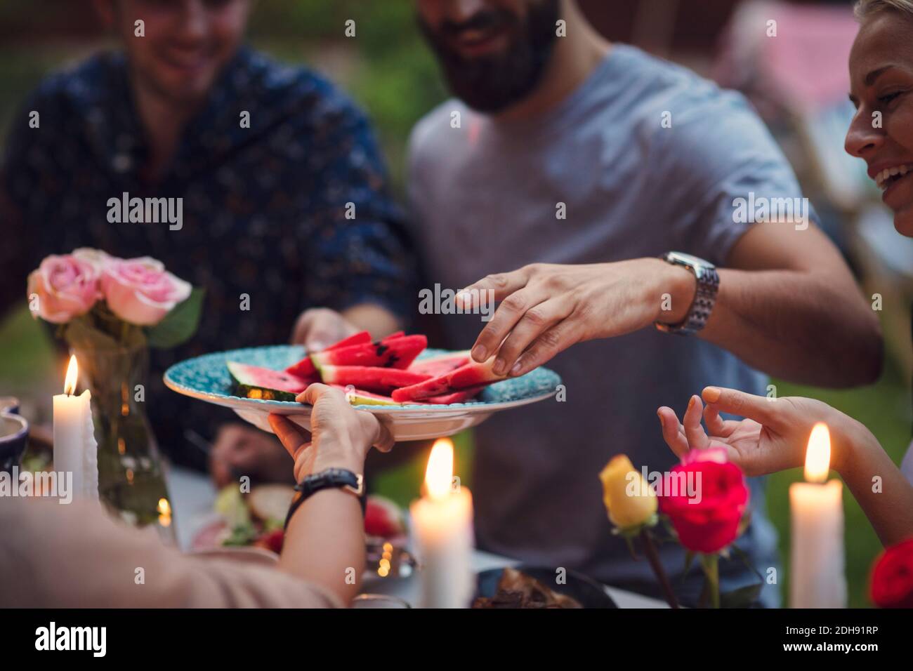 Immagine ritagliata di donna che serve fette di anguria agli amici a. festa in giardino Foto Stock