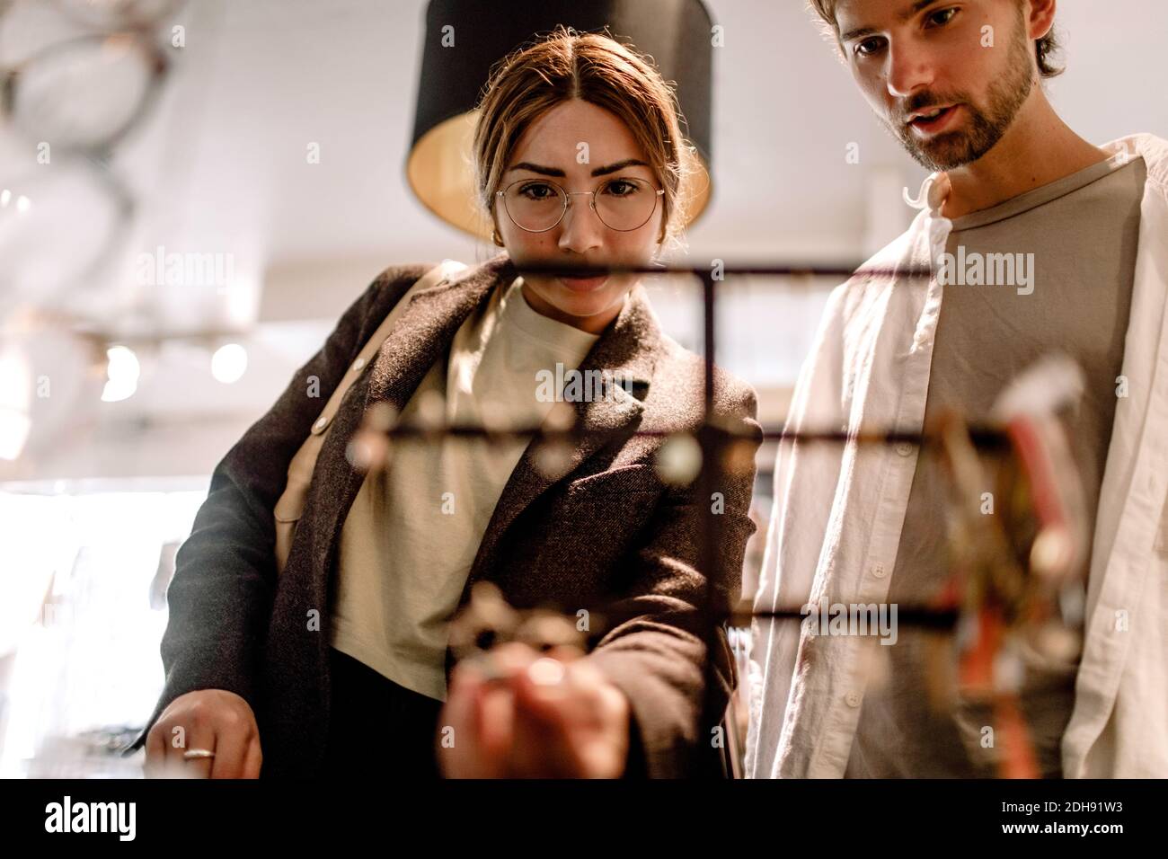 Uomo e donna che guardano gli occhiali nel negozio al dettaglio Foto Stock
