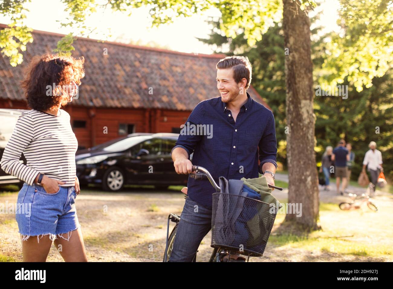 Uomo che parla con un'amica mentre si guida in bicicletta in cortile Foto Stock