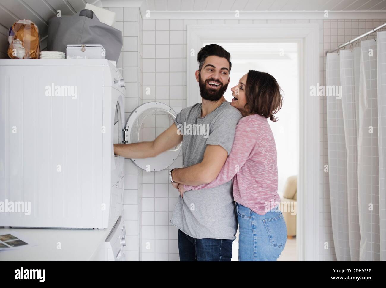 Felice coppia in piedi da lavatrice a casa Foto Stock