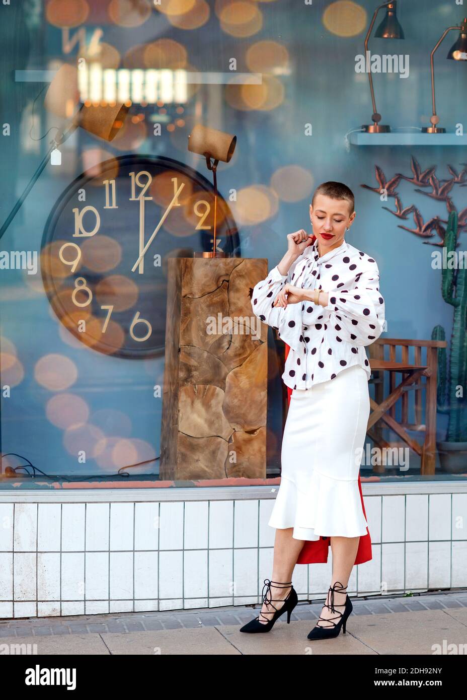 donna in blusa bianca e gonna, tenendo un cappotto rosso e aspettando  qualcuno vicino al mantello Foto stock - Alamy