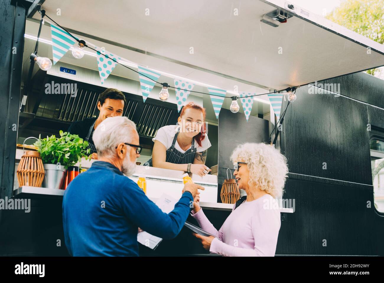 Sorridendo i proprietari che parlano con i clienti mentre si trovano in terra commerciale veicolo Foto Stock