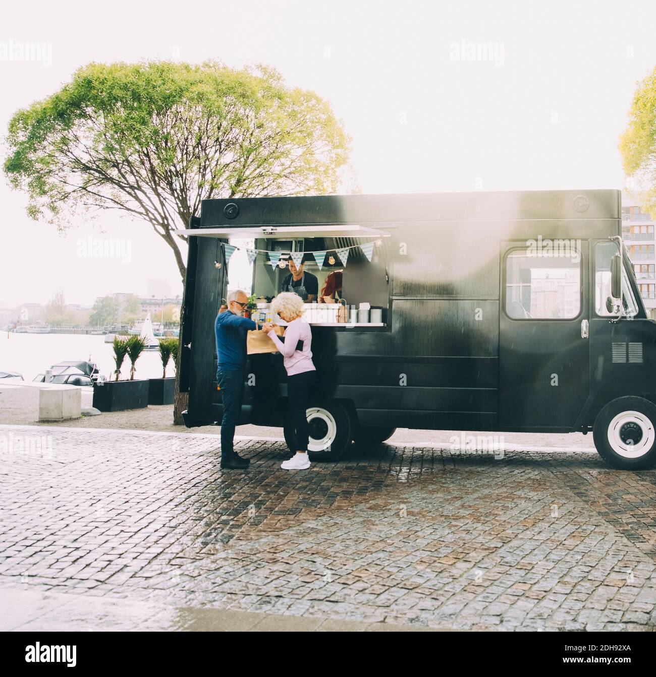 Il proprietario parla con i clienti senior mentre si trova in terra commerciale veicolo Foto Stock