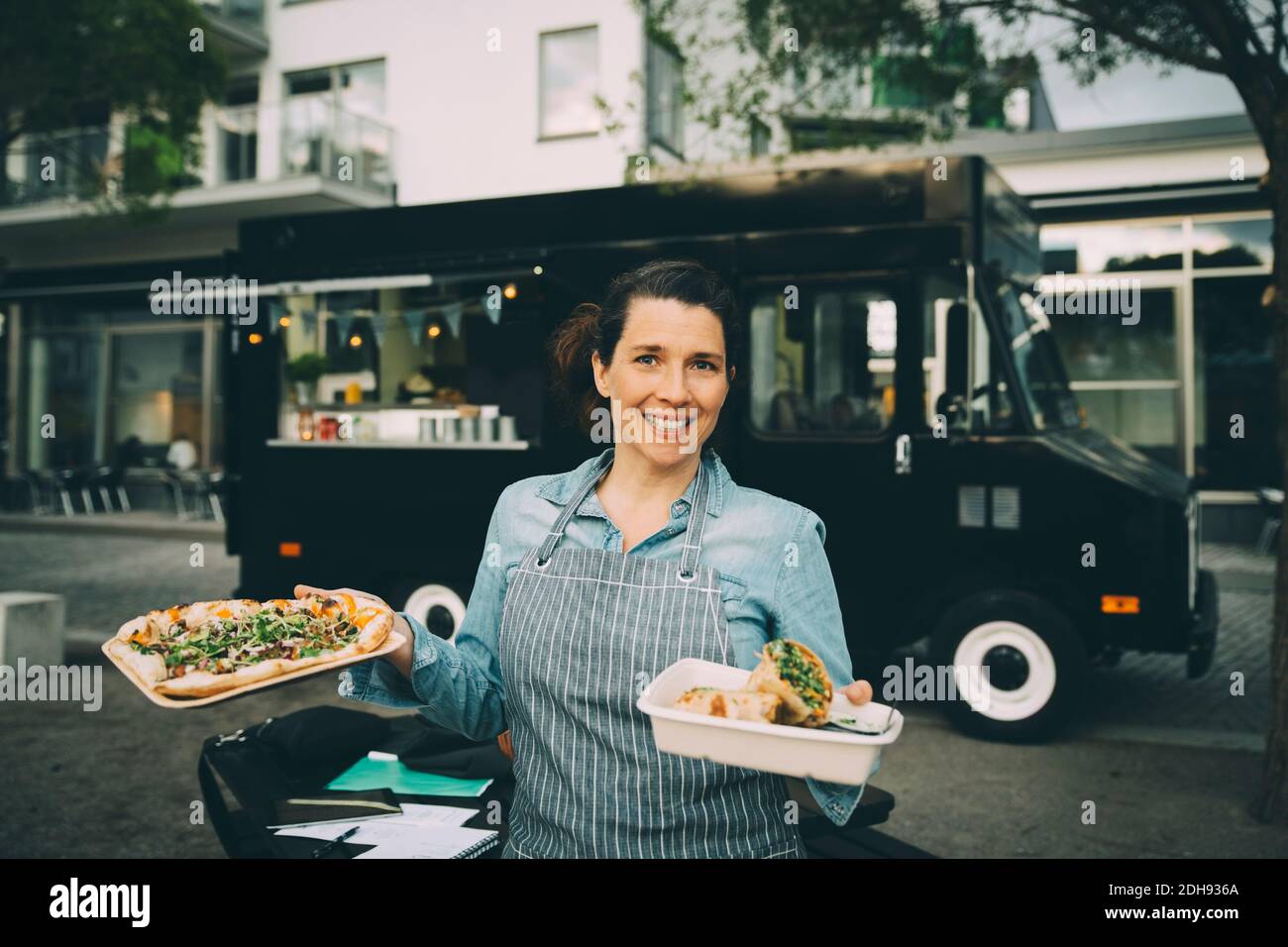 Ritratto di donna sorridente proprietario con cibo indiano di strada contro veicolo commerciale Foto Stock