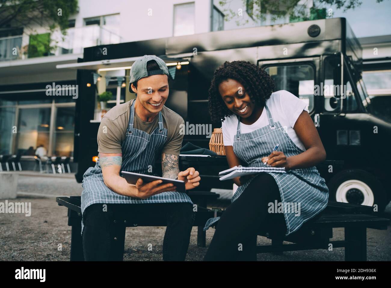 Sorridendo i proprietari di uomini e donne che lavorano contro il camion di cibo dentro città Foto Stock