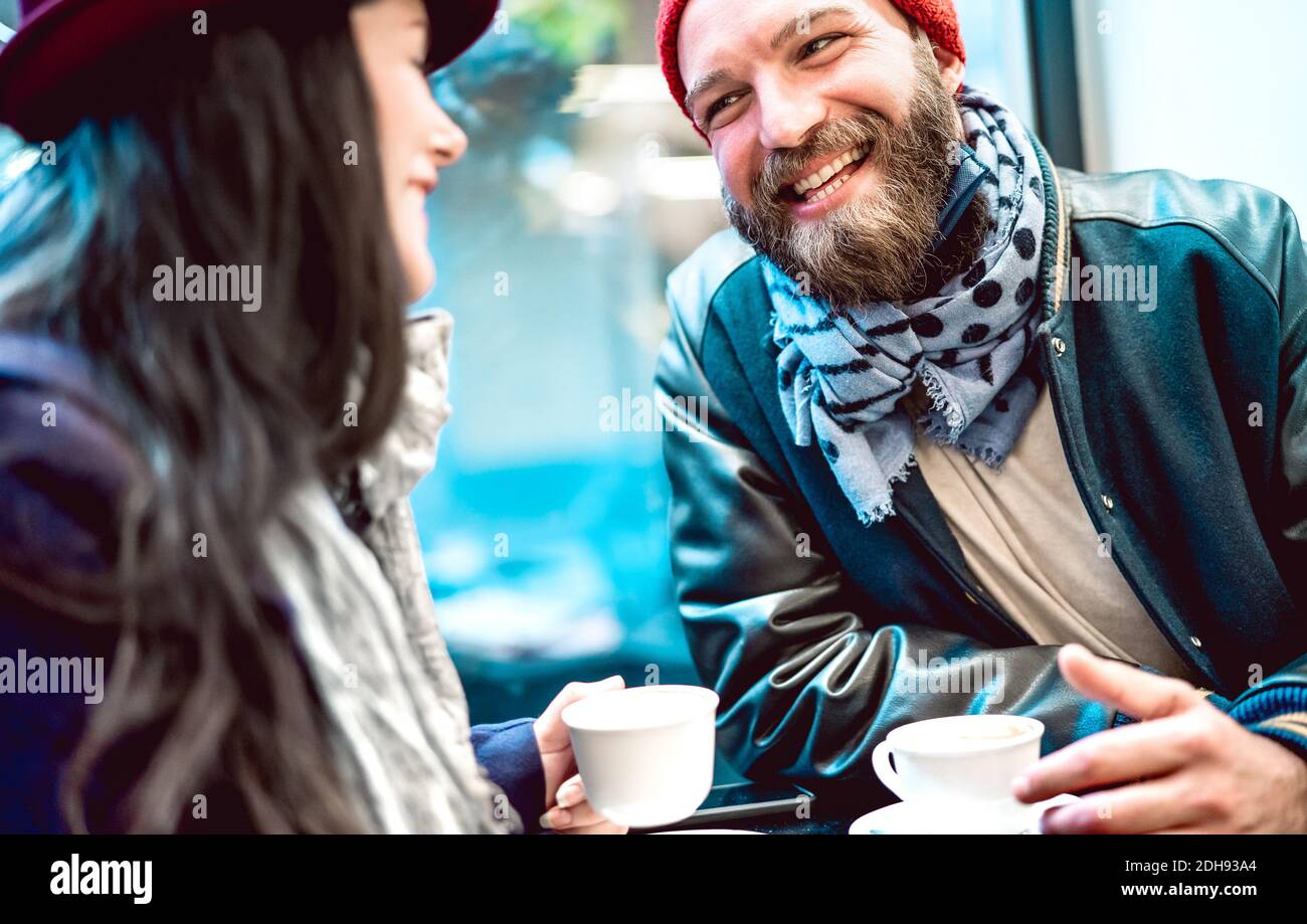 Una coppia felice che parla e si diverte insieme al bar caffetteria - concetto di stile di vita invernale con i giovani di umore positivo bere caffè italiano Foto Stock