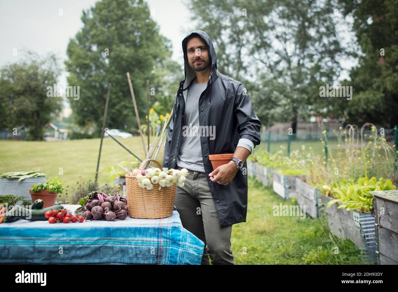 Ritratto di un uomo medio adulto in piedi da verdure appena raccolte sul tavolo al giardino urbano Foto Stock