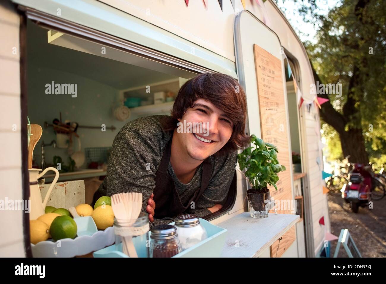 Ritratto di uomo felice proprietario appoggiato sulla vetrina di camion di cibo Foto Stock