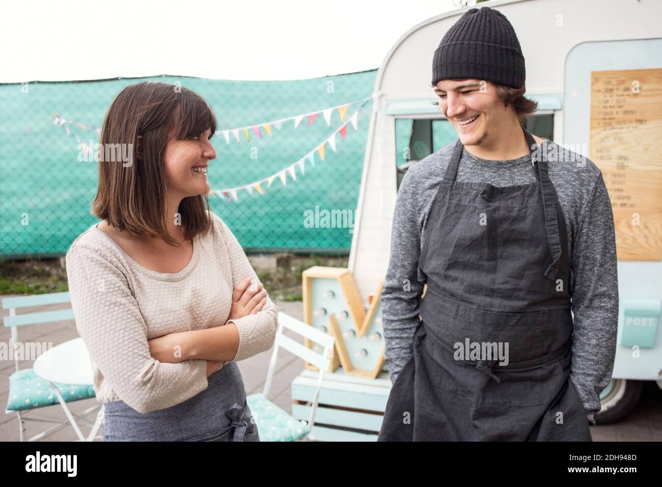 Felici proprietari di uomini e donne che parlano mentre si levano in piedi sulla strada camion per alimenti all'aperto Foto Stock